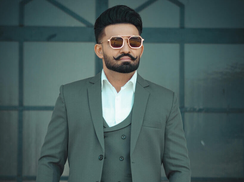 Resham Singh Anmol in formal suit wearing sunglasses posing confidently outdoors
